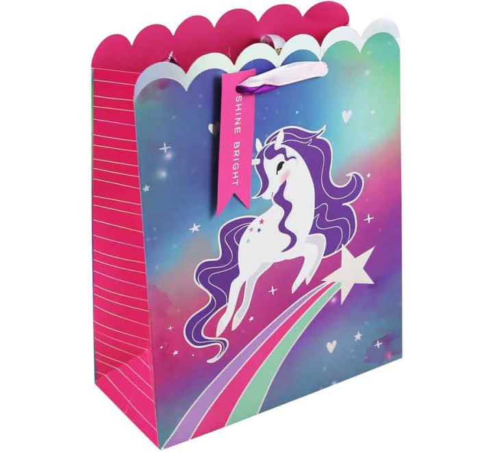 Gift bag featuring a white unicorn leaping over a rainbow shooting star on a colorful galaxy background with a scalloped pink top and “Shine Bright” tag.